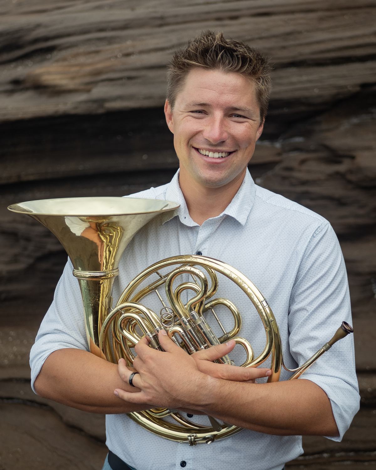 Brian KM smiling, holding his french horn
