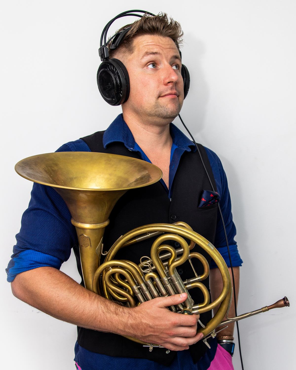 Brian KM holding his horn, wearing studio headphones